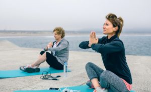 Young and senior woman exercising sitting outdoors