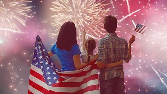 Family watching fireworks holding american flag