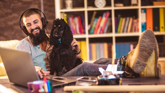man and dog sitting in front of laptop