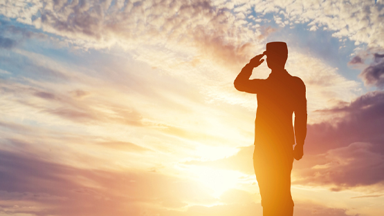 military man saluting in front of sunset