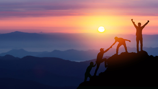 people helping one another climb a mountain