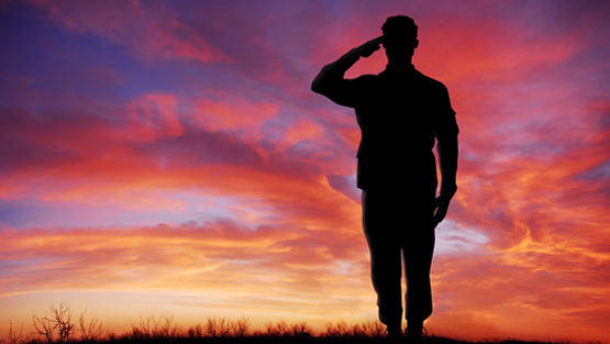 Man saluting in front of a sunset