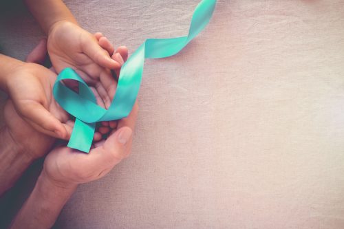 Hands holding a teal ribbon