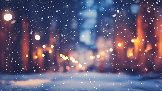 Soft snow falls in a lone street with warm street lamps as dusk falls