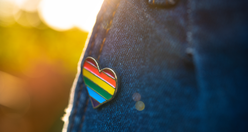 heart-shaped gay pride pin on jean jacket