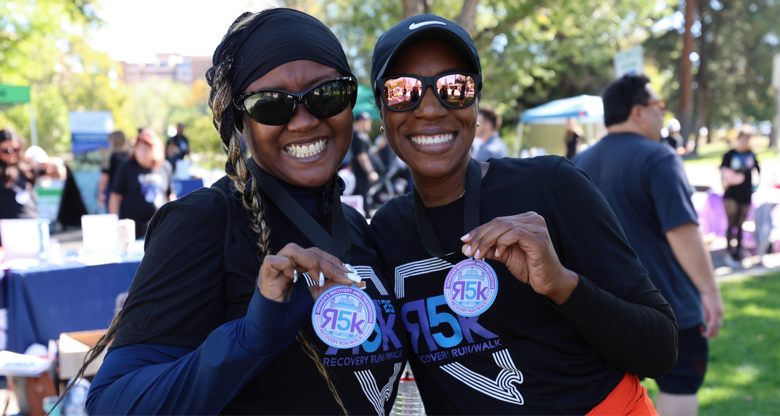 two women smiling holding R5k medals